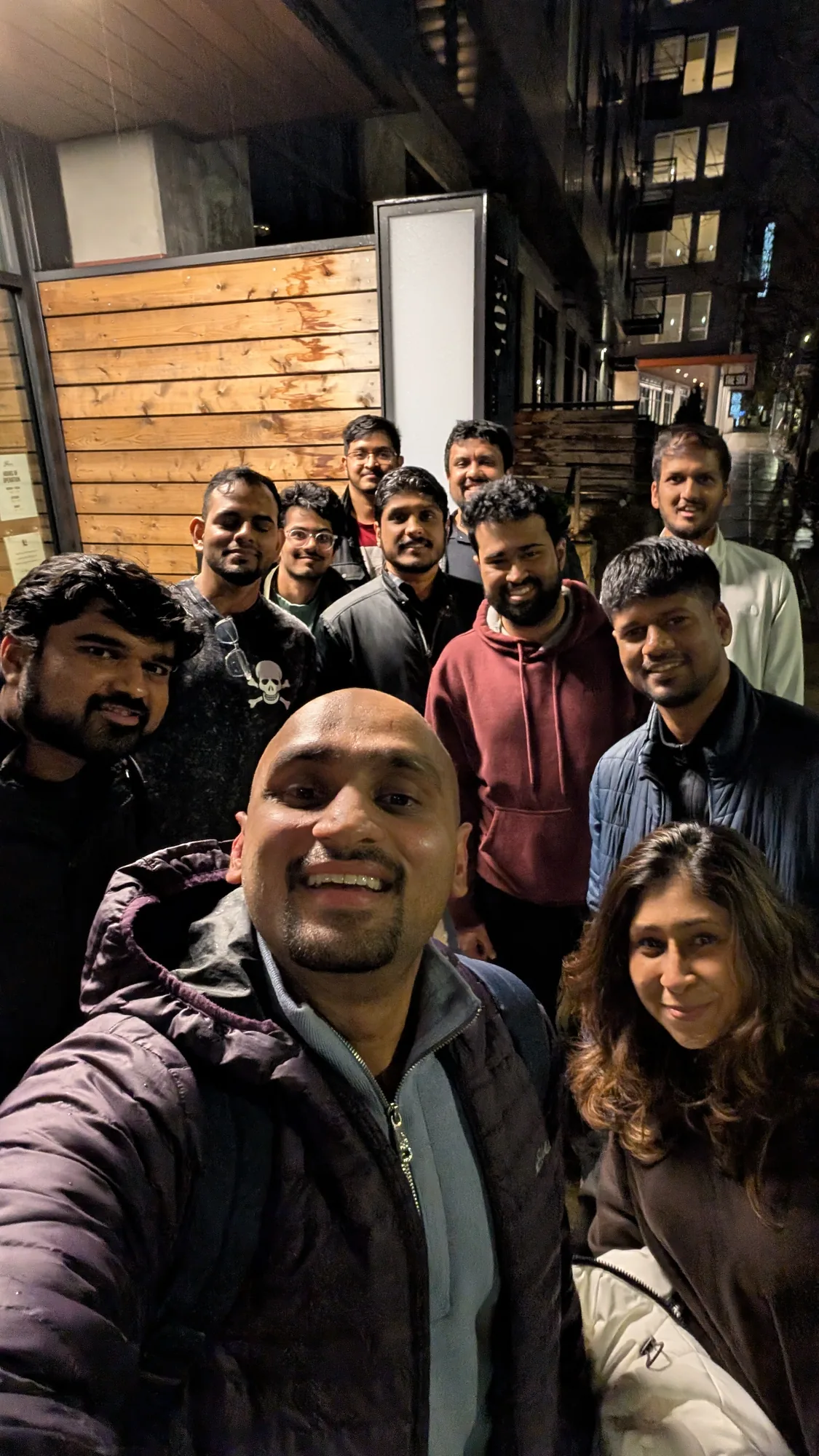 Ten club members crowded into a selfie on the pavement outside at night after a club night.